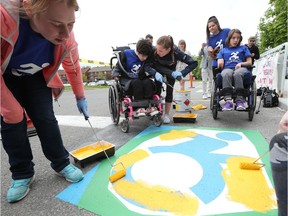 CHEO's We Club goes to work painting three parking spaces with new dynamic accessibility icons at CHEO on Friday.