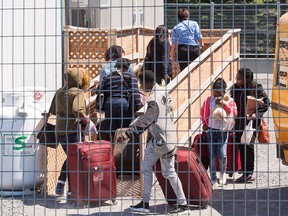 A group of asylum seekers arrives at temporary housing facilities at the Canadian border crossing in St. Bernard-de-Lacolle, Que., on May 9, 2018.