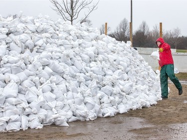 A volunteer tosses a sand bag onto the pile that continues to grow on Grandview Ave as the Ottawa River continues to rise with no let up for the next few days.