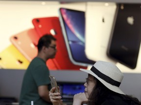 A customer looks at her iPhone in a store of U.S. tech company Apple in Beijing on Friday, May 10, 2019. U.S. President Donald Trump's latest tariff hike on Chinese goods took effect Friday and Beijing said it would retaliate, escalating a battle over China's technology ambitions and other trade tensions.