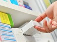 Closeup pharmacist hand holding medicine box in pharmacy drugstore.