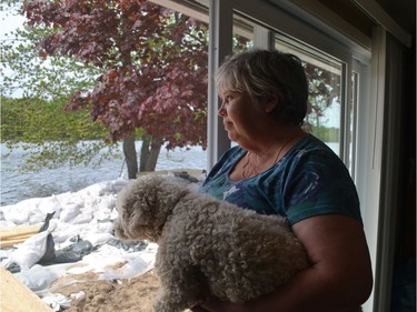 This was the second flood in as many years to hit Shannon Grove's home in Constance Bay. She looks out on the swollen river with her dog, Murphy on Saturday.