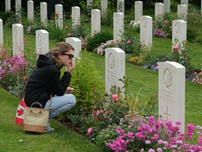 REVIERS, FRANCE - JUNE 05:  Lise Belanger, 18, wipes an eye as she kneels at the gravestone of her great-uncle, Roger "Sonny" Firman, at the Commonwealth War Graves Commissions Beny-sur-Mer Canadian War Cemetery in Normandy on June 05, 2019 near Reviers, France.