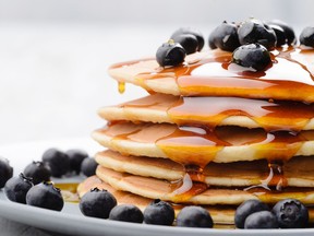 Plate of delicious pancakes  with fresh blueberries and maple syrup.