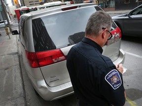 Parking control officer Danny Lafrance writes a ticket for a vehicle parked in a no-stopping zone on Slater Street near Bank Street on Monday.