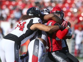 Redblacks defenders wrap up Stampeders running back Don Jackson on a rushing attempt during Saturday's game in Calgary.