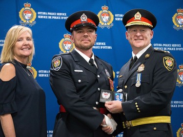 (From left) Diane Deans, Chair of the Ottawa Police Services Board, recruit Chad Fawcett and Interim Police Chief Steven Bell pose for a photo as 88 Ottawa Police Service recruits received their police badges as part of the graduating ceremony held at the EY Centre.