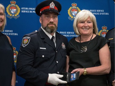 Jeffrey Ryan (left) is presented his badge by his mom, retired Ottawa Police Service member Gayle Ryan with Interim Police Chief Steven Bell (right) at a graduating ceremony held at the EY Centre.
