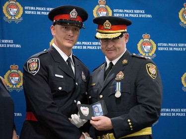 Adam Morin (left) is presented his badge by Interim Police Chief Steven Bell (right) at a graduating ceremony held at the EY Centre.