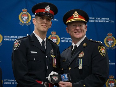 Sean Cunningham (left) is presented his badge by Interim Police Chief Steven Bell (right) at a graduating ceremony held at the EY Centre.