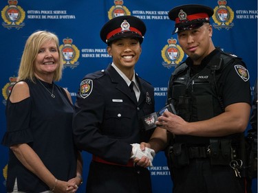 Jimmy Fang (centre) is presented his badge by Constable Evan Hung (right) with Diane Deans, Chair of the Ottawa Police Services Board (left).
