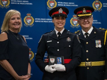Shannon Hilton (centre) is presented her badge by her grandfather and former Belleville Police Chief David Klenavic (right) with Diane Deans, Chair of the Ottawa Police Services Board (left).