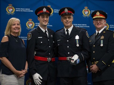 Stephen Irvine (second from left) is presented his badge by his father Constable John Irvine (second from right) with Interim Police Chief Steven Bell (right) and Diane Deans, Chair of the Ottawa Police Services Board (left).