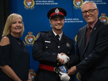 Jason McCarthy (centre) is presented his badge by former Ottawa Police Chief Brian Ford (right) with Diane Deans, Chair of the Ottawa Police Services Board (left).