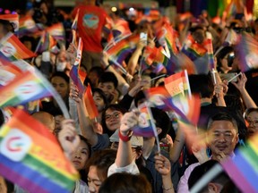 People wave rainbow flags during a mass wedding banquet for gay couples in front of the Presidential Palace in Taipei on May 25, 2019.