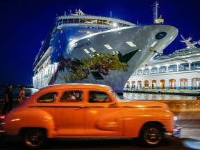 An old American car passes in front of a cruise docked at Havana's Harbour, on June 5, 2019. -