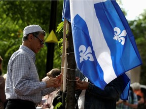 A man raises a flag as people protest Quebec's new Bill 21, which will ban teachers, police, government lawyers and others in positions of authority from wearing religious symbols such as Muslim head coverings and Sikh turbans, in Montreal, Quebec, Canada, June 17.  REUTERS/Christinne Muschi