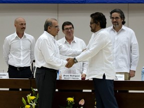 In this Dec. 15, 2015 file photo, Norwegian diplomat Dag Nylander, far left, watches as Humberto de la Calle, front left, head of Colombia's government peace negotiation team, shakes hands with Ivan Marquez, chief negotiator of the Revolutionary Armed Forces of Colombia, or FARC, after signing an agreement on how to address the needs of eight million victims, at the Convention Palace in Havana, Cuba.