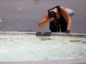 A woman cools off at a fountain.