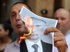 A participant burns a portrait of Russia's President Vladimir Putin during a rally to protest against the visit of the Russian delegation in Tbilisi, Georgia June 20, 2019.