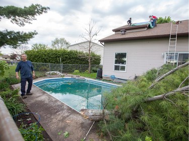 David Redmond surveys the damage of his home while his son and friends install tarps over a hole in the roof of a home on Singleton Way as a reported tornado touched down in the Orléans suburb of Ottawa on Sunday evening. Wayne Cuddington / Postmedia