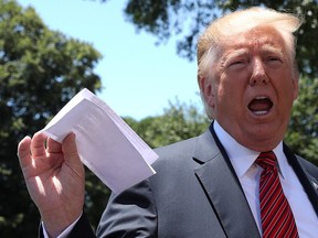 U.S. President Donald Trump holds up a copy of a deal with Mexico on immigration and trade as he speaks to the news media prior to departing for travel to Iowa from the White House in Washington, U.S., June 11, 2019.