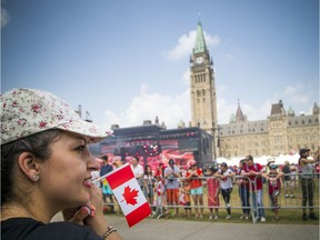 Canada Day celebrations took over the downtown core of Ottawa Sunday July 1, 2018. Ali Iranpour holds a Canada flag awaiting the dignitaries arrival on Parliament Hill prior to the noon show.   Ashley Fraser/Postmedia