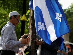 A man raises a flag as people protest Quebec's new Bill 21, which will ban teachers, police, government lawyers and others in positions of authority from wearing such religious symbols as Muslim head coverings, yarmulkas and Sikh turbans.