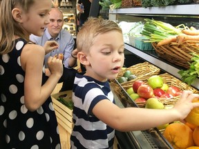 Jean-Yves Duclos, the federal minister of families, children and social development, helps Orin Ireland, 4, and his sister Emmy, 6, stock the shelves at The Grocery Basket in Kingston, Ont. on Thursday, July 18, 2019. Duclos was in Kingston to promote coming increases in the Canada Child Benefit.