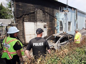Belleville fire prevention officer Norm Mitts watches as tow truck operators remove a burnt car at a fire scene on South Park Street in Belleville