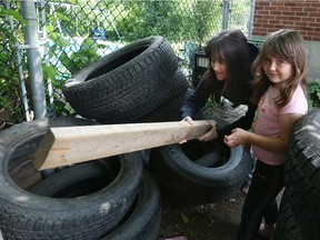 Lianna Levesque and her daughter Maddisin-Lynn try to poke the rats out of tires near their rental home in Overbrook on Tuesday.