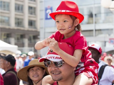 Phyrun Bun holds his daughter-in-law Pony Chan, 3, on his shoulders as Canada Day activities are in full swing through out the downtown core.