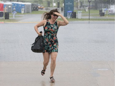 Renée Duguay, 42, scurries for cover after arriving at the Canadian War Museum during the severe weather warning as the second day of RBC Bluesfest gets going on Friday evening.