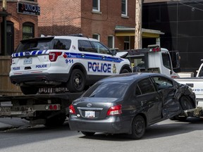 Tow trucks remove vehicles following a collision between an Ottawa Police Service SUV and a compact car near the intersection of Bank Street and Cooper Street on Friday.