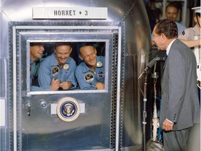 (FILES) This July 24, 1969, file photo from NASA, shows then-U.S. President Richard Nixon welcoming the Apollo 11 astronauts aboard the USS Hornet. The three were confined to the Mobile Quarantine Facility. Left to right:  Neil Armstrong, commander; Michael Collins, command module pilot; and Edwin Aldrin Jr., lunar module pilot.