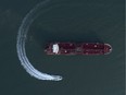 In this Sunday, July 21, 2019 photo, an aerial view shows a speedboat of Iran's Revolutionary Guard moving around the British-flagged oil tanker Stena Impero which was seized in the Strait of Hormuz on Friday by the Guard, in the Iranian port of Bandar Abbas. Global stock markets were subdued Monday while the price of oil climbed as tensions in the Persian Gulf escalated.