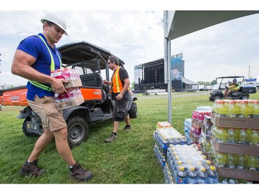 Adam Beveridge, left, and Jan Brocks, right, stock a booth with drinks as the 25th anniversary edition of Bluesfest gets ready to open on Thursday evening.  Photo by Wayne Cuddington / Postmedia