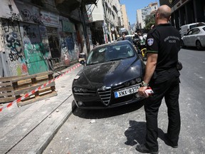 A police officer stands on a street next to a damaged car following an earthquake in Athens, Greece, July 19, 2019.