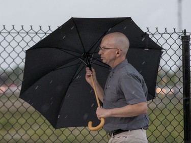 A pedestrian on Booth Street carries his umbrella during a severe thunderstorm warning that delayed Bluesfest once again on Day 7. Photo by Wayne Cuddington/ Postmedia