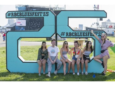 From left, Tibet Khan, Mason McGuire, Taylor Johnson, Qiara St. Amand, Odessa Johnson, and Abby Mackenzie pose for a quick photo on the Bluesfest sign before heading to the City Stage as the 25th anniversary edition of RBC Bluesfest gets underway on the grounds of the Canadian War Museum in Lebreton Flats. Photo by Wayne Cuddington/ Postmedia