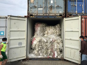 This handout photo taken on July 16, 2018 and released on July 17, 2019 by the Cambodian Ministry of Environment shows workers openinng a container loaded with plastic waste after the shipment arrived at Sihanoukville port in Preah Sihanouk province. - Cambodia will return about 1,600 tonnes of plastic waste to US and Canada after the rubbish were found at a seaport, an official said on July 17.