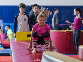 FILE PHOTO: Students play on gymnastics equipment during an announcement event for new programs. Not all families could afford the fees.