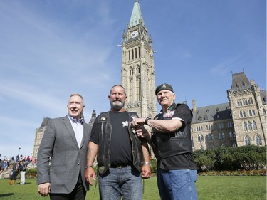 Retired major-general Lewis MacKenzie, right, presents the Canadian Peacekeepers Service Medal and the Commander-in-Chief Unit Commendation to James Gordon, center, along with retired Lieutenant-General Peter Devlin as part of "The Rolling Barrage" charity motorcycle ride on Parliament Hill on Sunday, August 11, 2019.