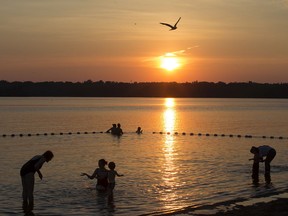 The setting sun cast a glow across Westboro Beach on the Ottawa River as a number of bathers take advantage of the cool river to escape summer's heat.