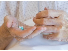 Elderly patient taking pills with water in hospital room.