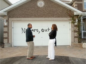 Rideau-Rockcliffe Coun. Rawlson King talks with Dr. Xaviere Kuate last May, after Kuate's garage door was spray-painted with a racist message. King is proposing the city establish an anti-racism secretariat.