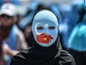 A demonstrator wearing a mask painted with the colours of the flag of East Turkestan and a hand bearing the colours of the Chinese flag attends a protest of supporters of the mostly Muslim Uighur minority and Turkish nationalists to denounce China's treatment of ethnic Uighur Muslims during a deadly riot in July 2009 in Urumqi, in front of the Chinese consulate in Istanbul