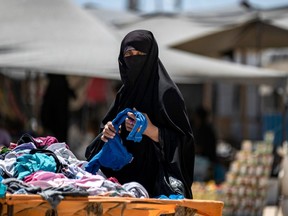 A Syrian woman picks clothes in the al-Hol camp in al-Hasakeh governorate in northeastern Syria, on August 08, 2019.