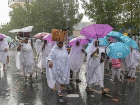 Muslim pilgrim walk in the rain near Mount Arafat, also known as Jabal al-Rahma (Mount of Mercy), southeast of the Saudi holy city of Mecca, as the climax of the Hajj pilgrimage approaches on August 10, 2019. - Arafat is the site where Muslims believe the Prophet Mohammed gave his last sermon about 14 centuries ago,