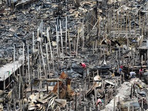 TOPSHOT - A resident gathers charred debris in a slum in Dhaka on August 18, 2019, after a fire broke out late on August 17 at Mirpur neighbourhood. - At least 10,000 people are homeless after a massive fire swept through a crowded slum in the Bangladesh capital and destroyed thousands of shanties, officials said on August 18.